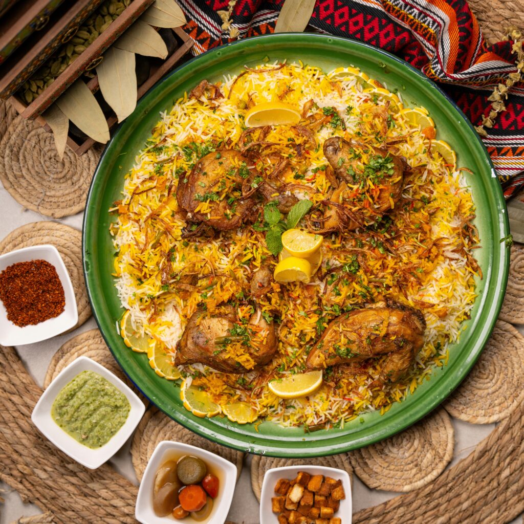 pexels-photo-17696653-17696653 Top view of a vibrant chicken biryani dish with saffron rice and assorted condiments.
